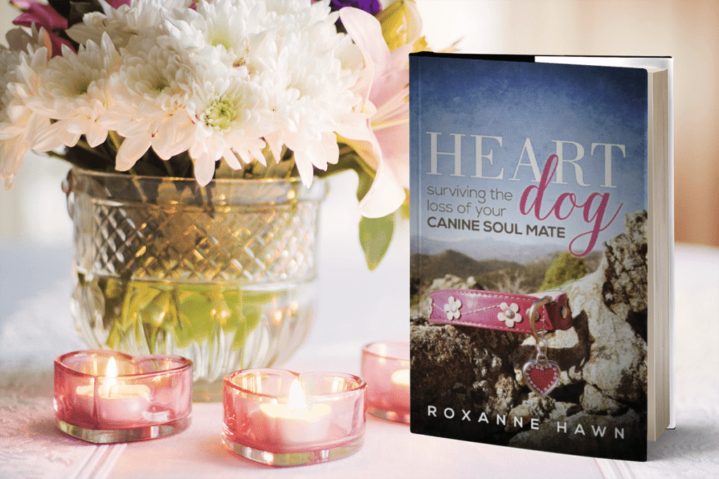Heart dog surviving the loss of your canine soul mate by roxanne hawn book next to a vase with mostly white flowers and 2 heart-shaped candles on the table